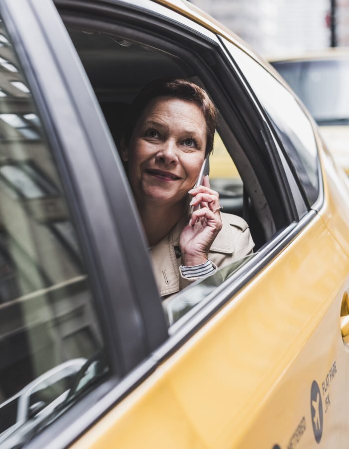 USA, New York City, smiling woman in taxi on cell phone